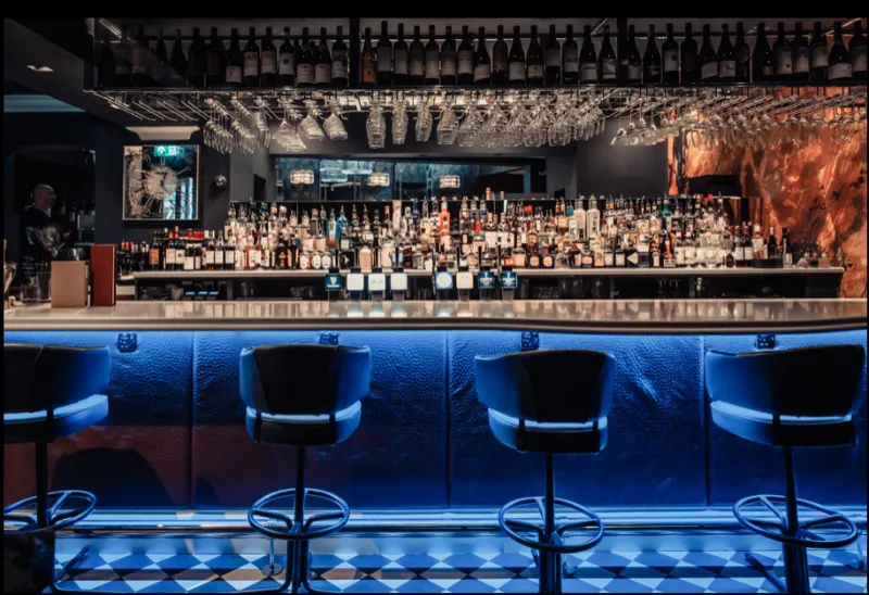 The bar at CuVée VIII: a back wall of bottles and a blue-lit bar front