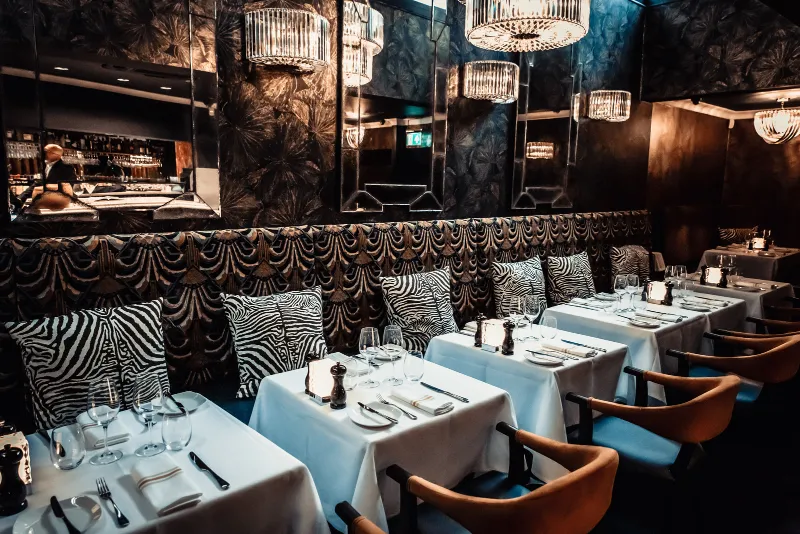 The dining room at CuVée VIII: zebra-print banquettes, white tablecloths and chandeliers