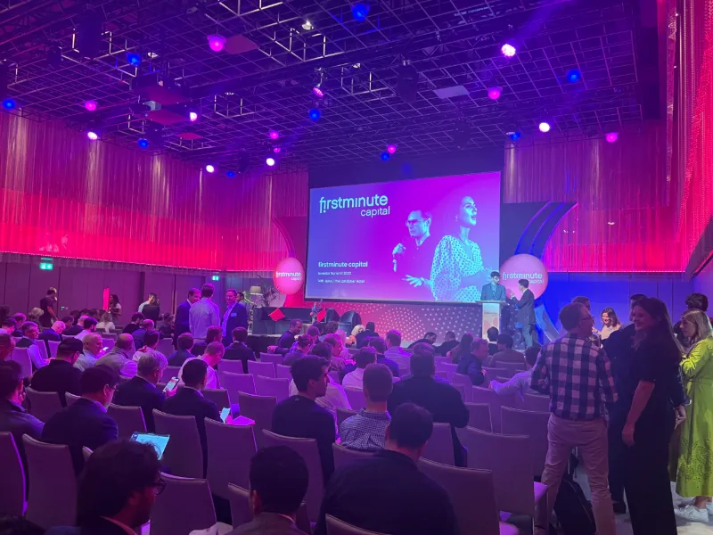 A firstminute capital event in a pink-lit hall