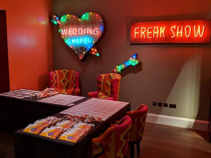 “Freak Show” and “Wedding Chapel” neon over a check-in table
