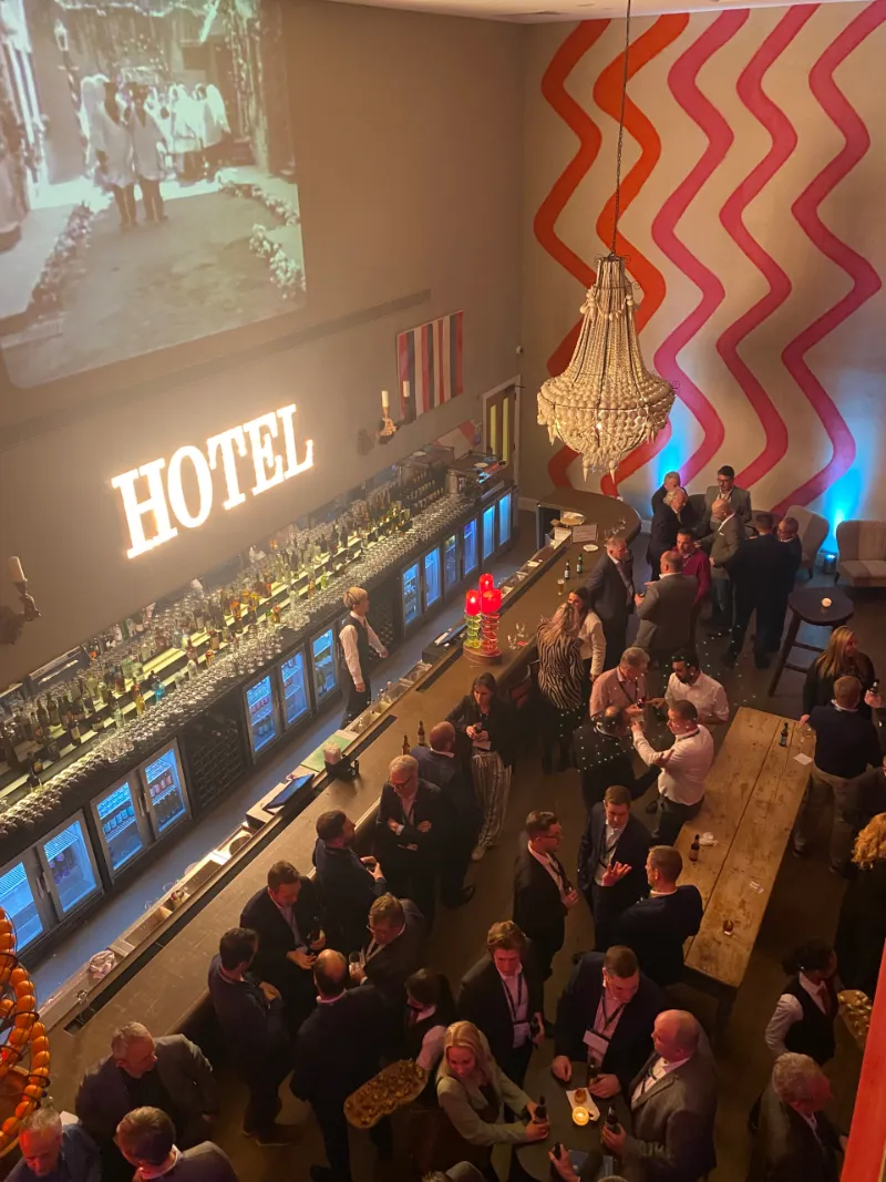 A packed bar under a big “HOTEL” neon sign