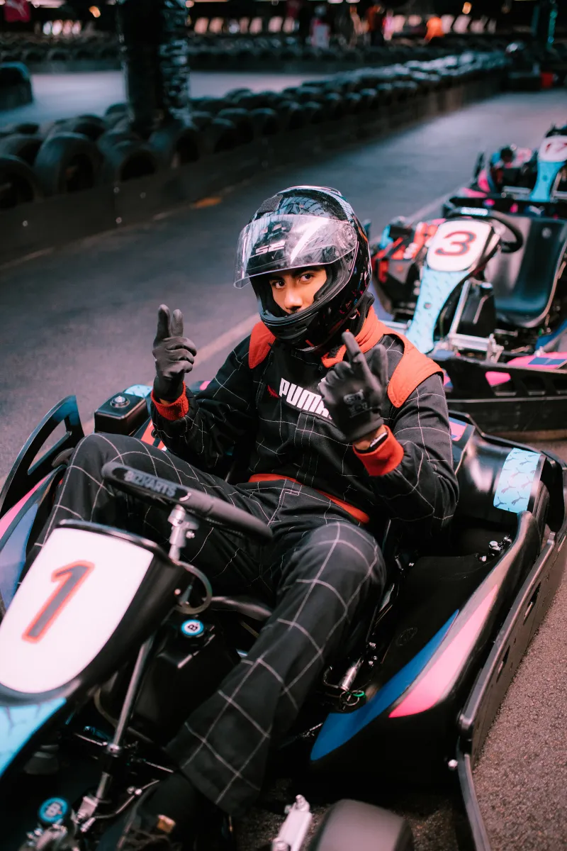 A racer in PUMA overalls in a kart, giving a thumbs up