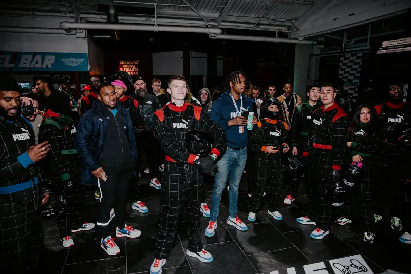 Racers in overalls on an indoor karting track at a PUMA event