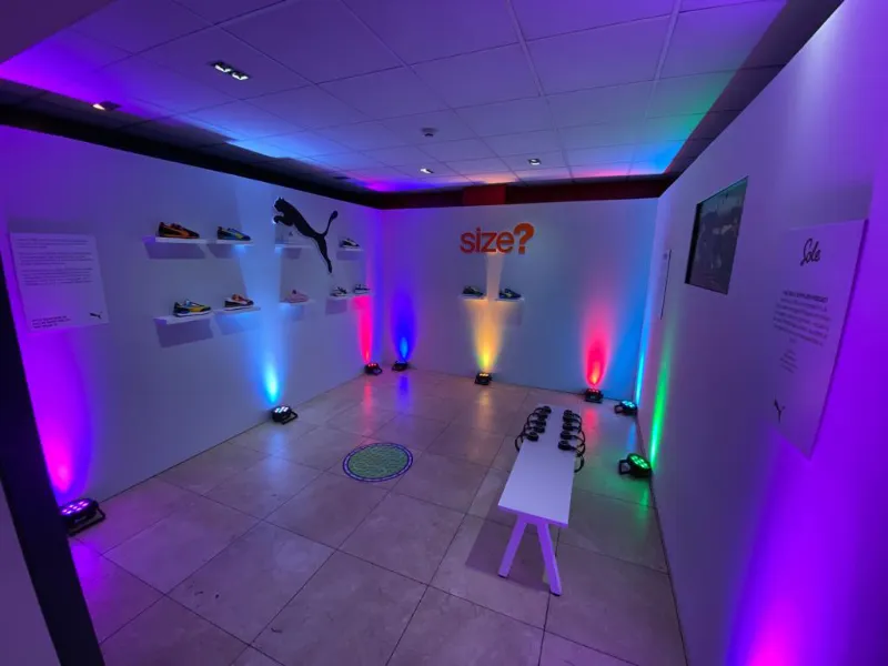 A PUMA × size? launch space, with trainers on the walls and coloured uplights